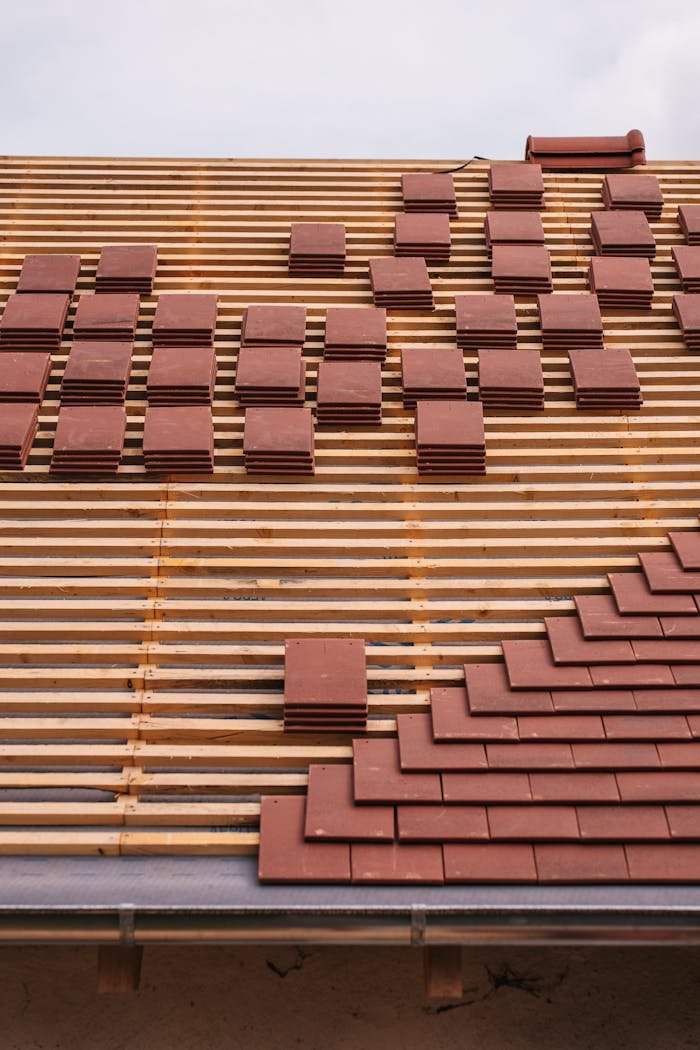 Mastering the First Impression: Your intriguing post title goes here Close-up of red clay tiles being placed on a roof, showcasing construction and craftsmanship.