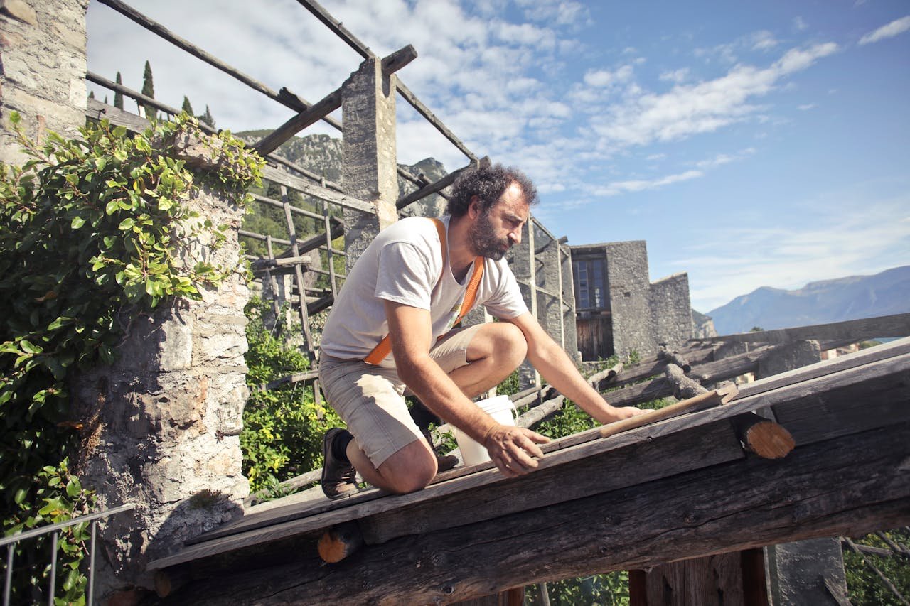 The Art of Drawing Readers In: Your attractive post title goes here A man kneeling on a rooftop under construction in a picturesque mountainous landscape on a sunny day.